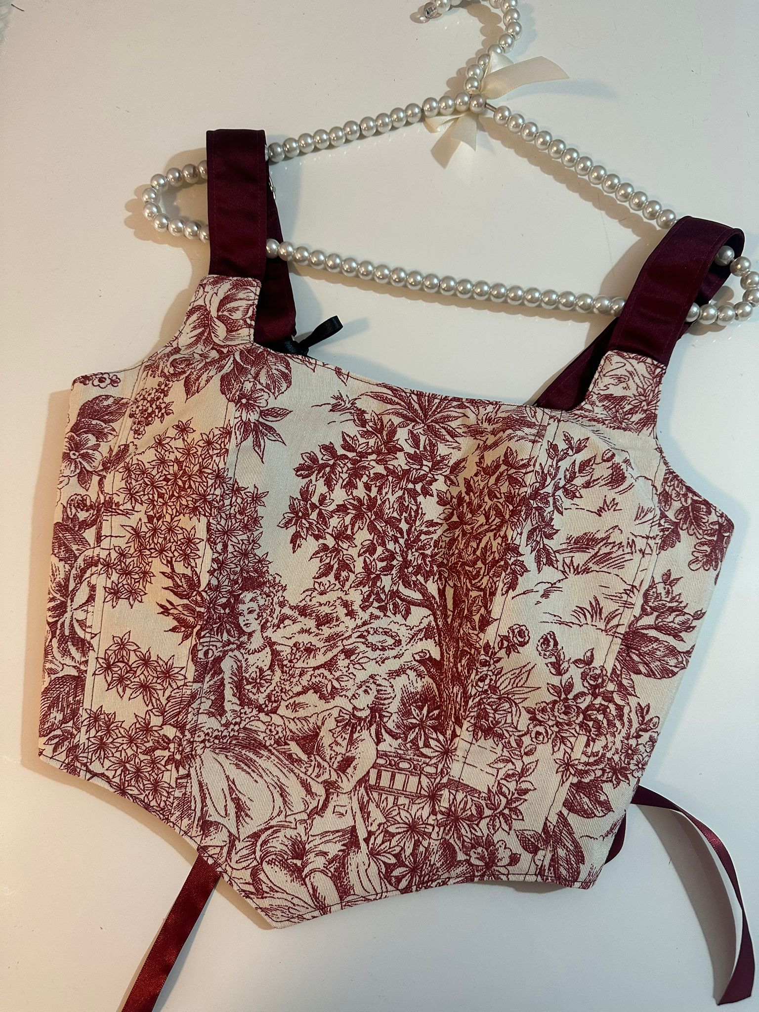 Floral patterned corset top with red and beige colors on a white background