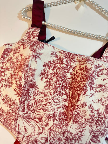 Red floral patterned corset top on a hanger with pearls