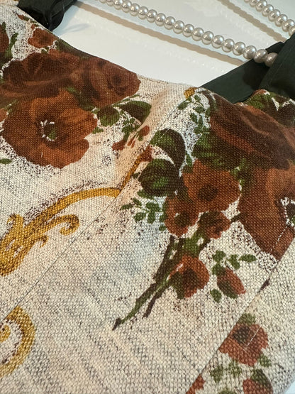 Close-up of a floral patterned fabric with brown flowers and green leaves.