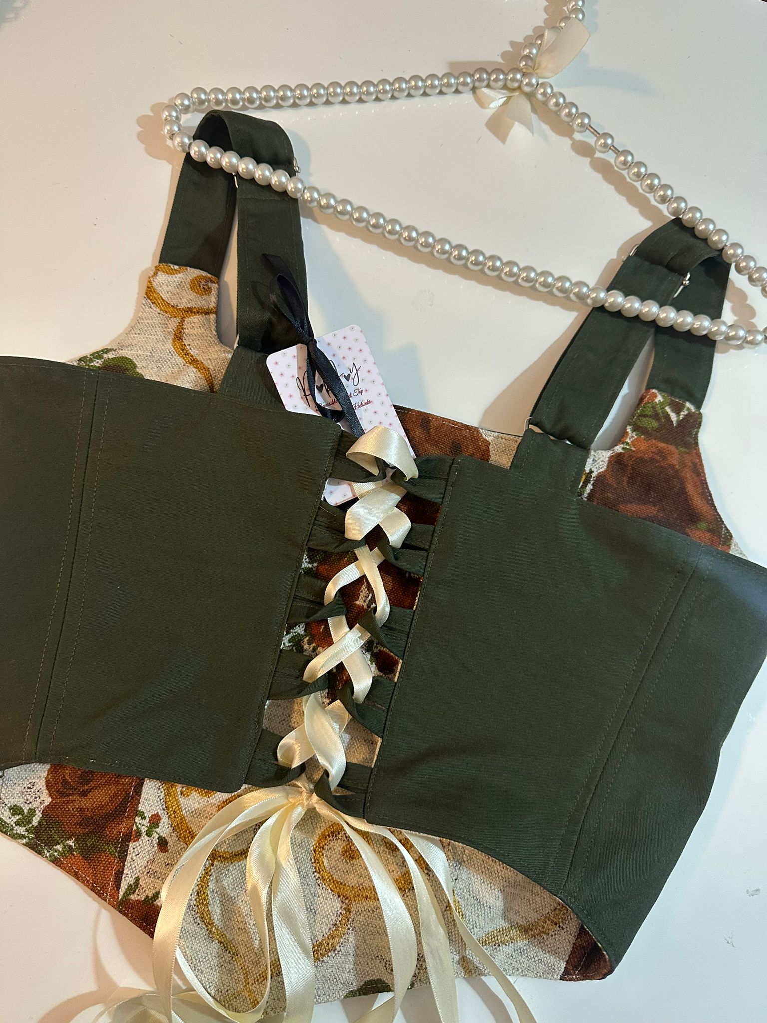 Black lace-up corset top with decorative ribbons on a patterned surface