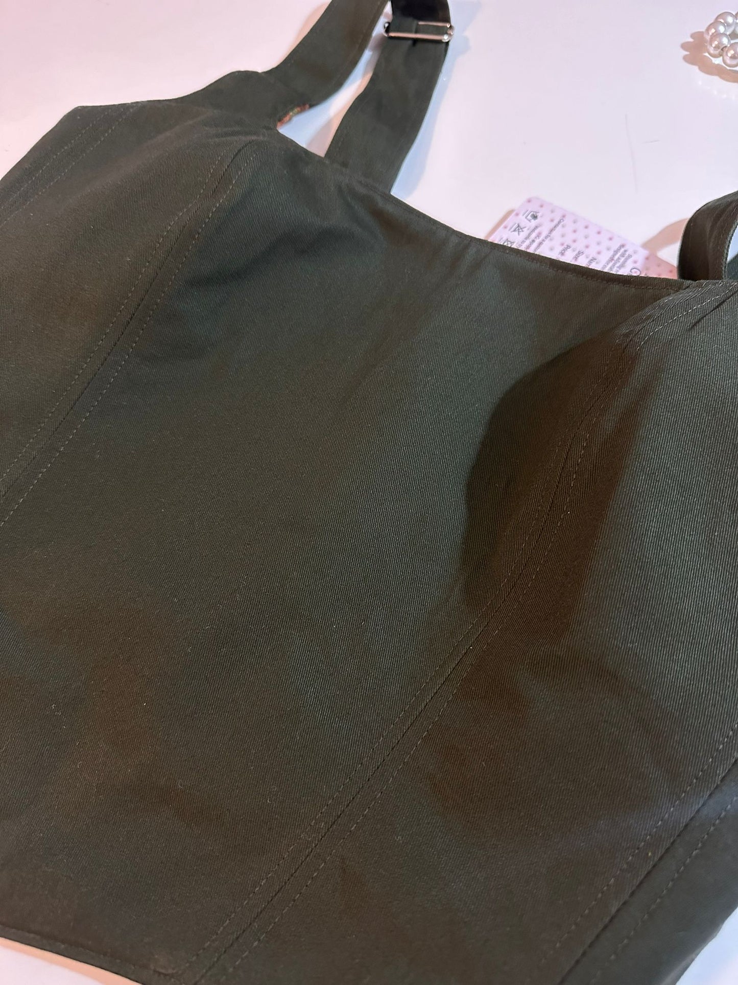 Green corset top on a light pink background