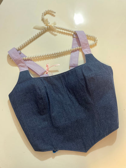 Denim corset top with pink straps on a beige background