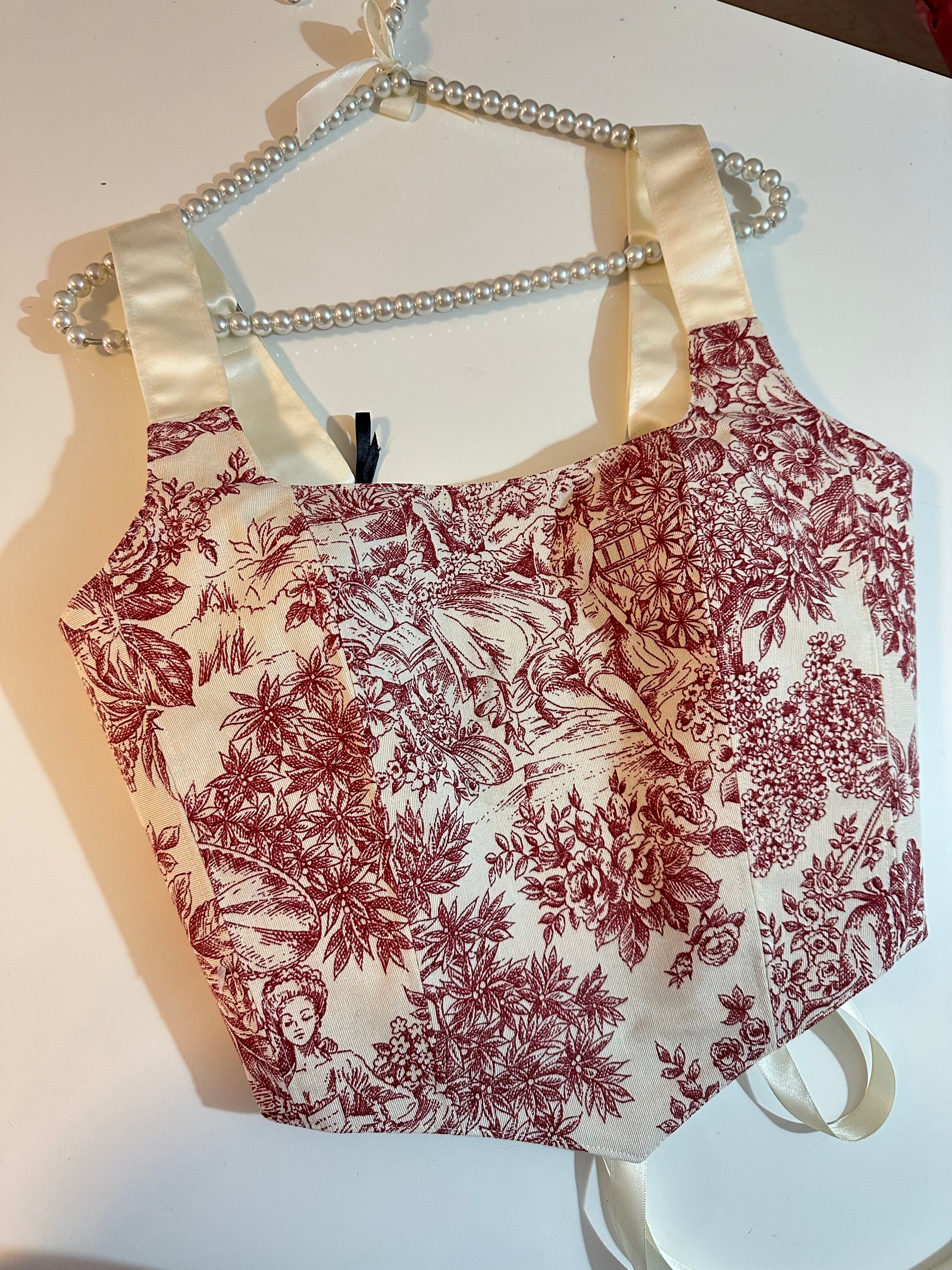 Floral-patterned corset top with a white strap on a white background