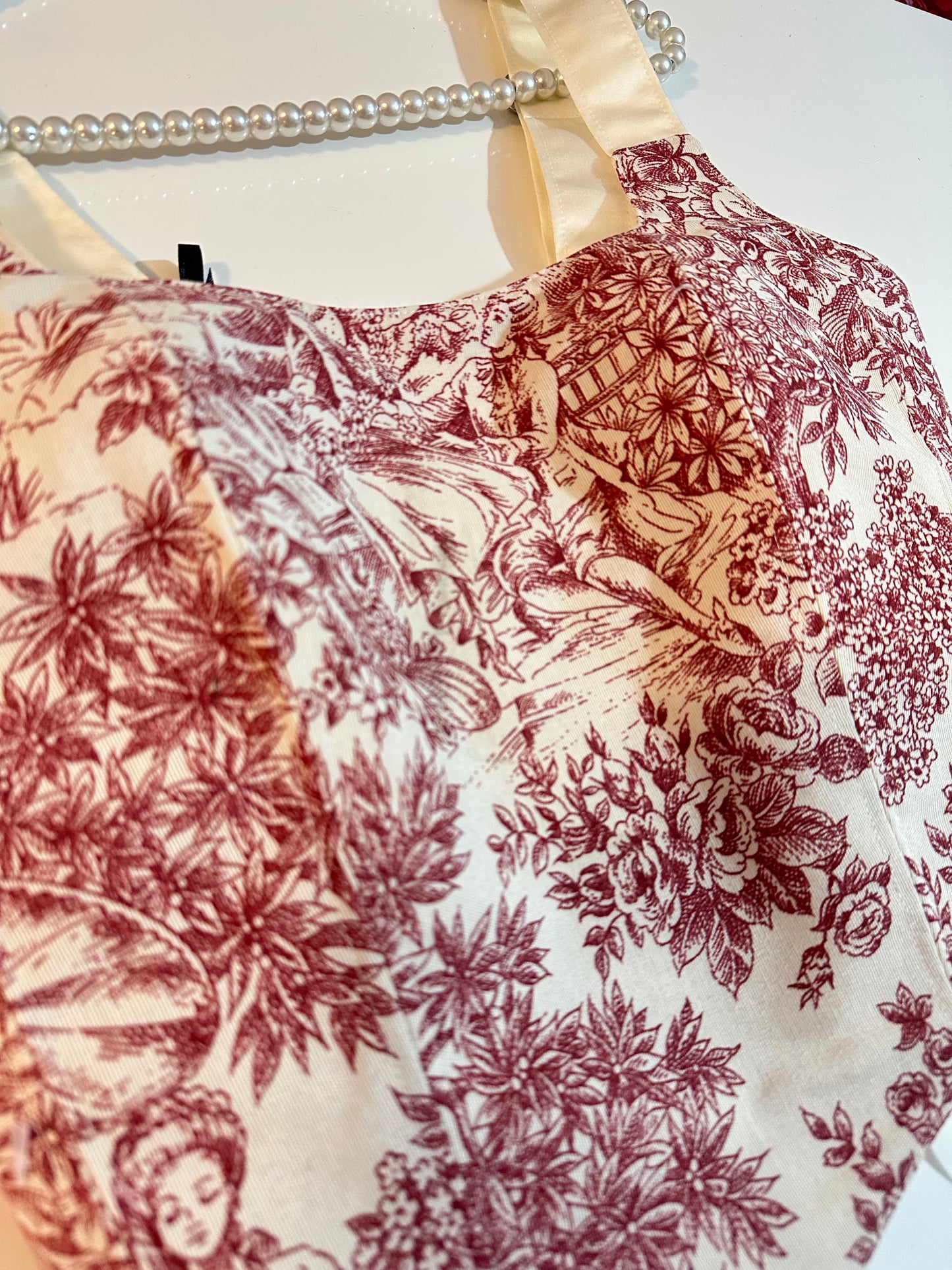 Close-up of a fabric with vintage-style floral and nature print on a white background.