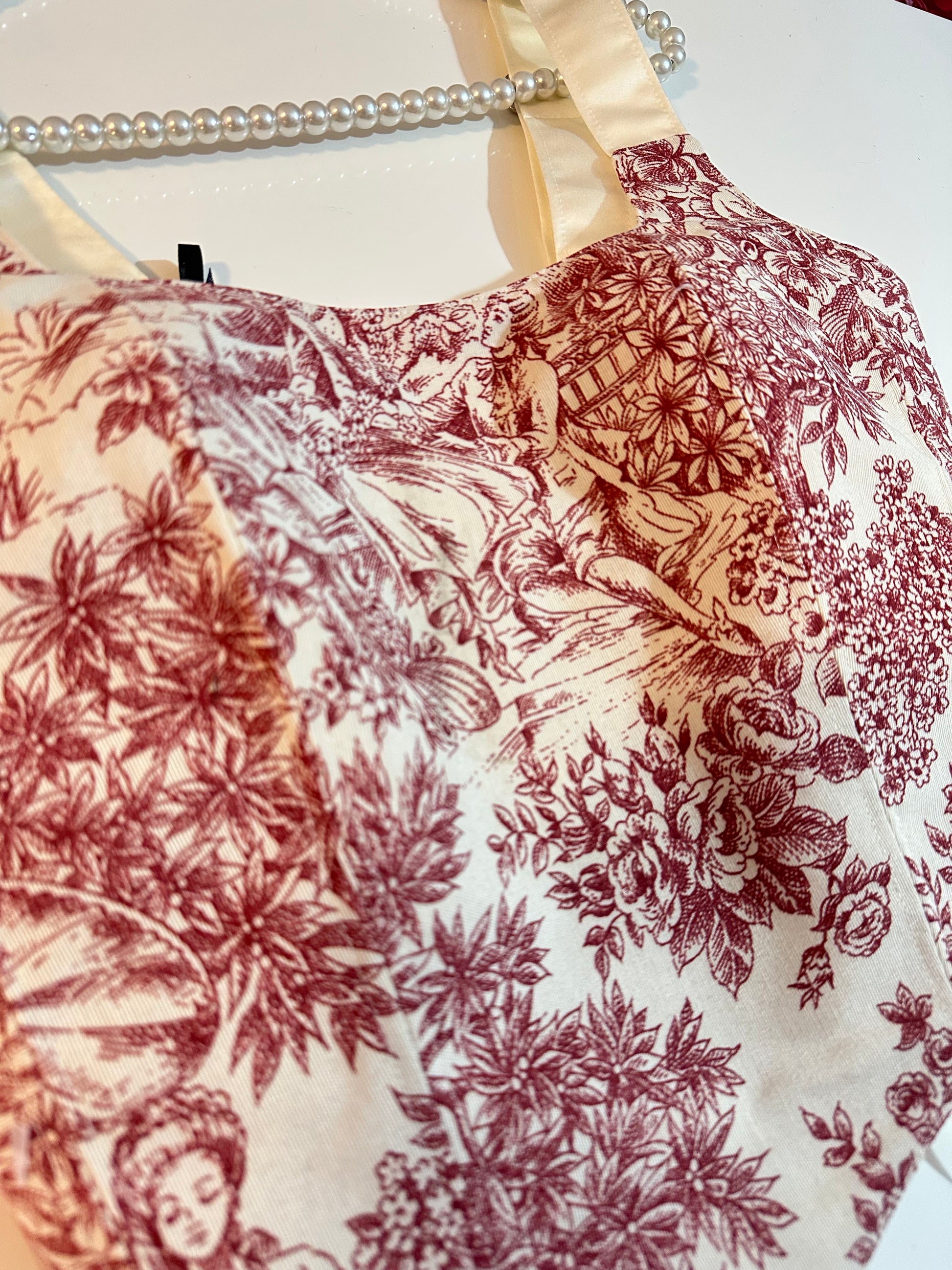 Close-up of a fabric with vintage-style floral and nature print on a white background.