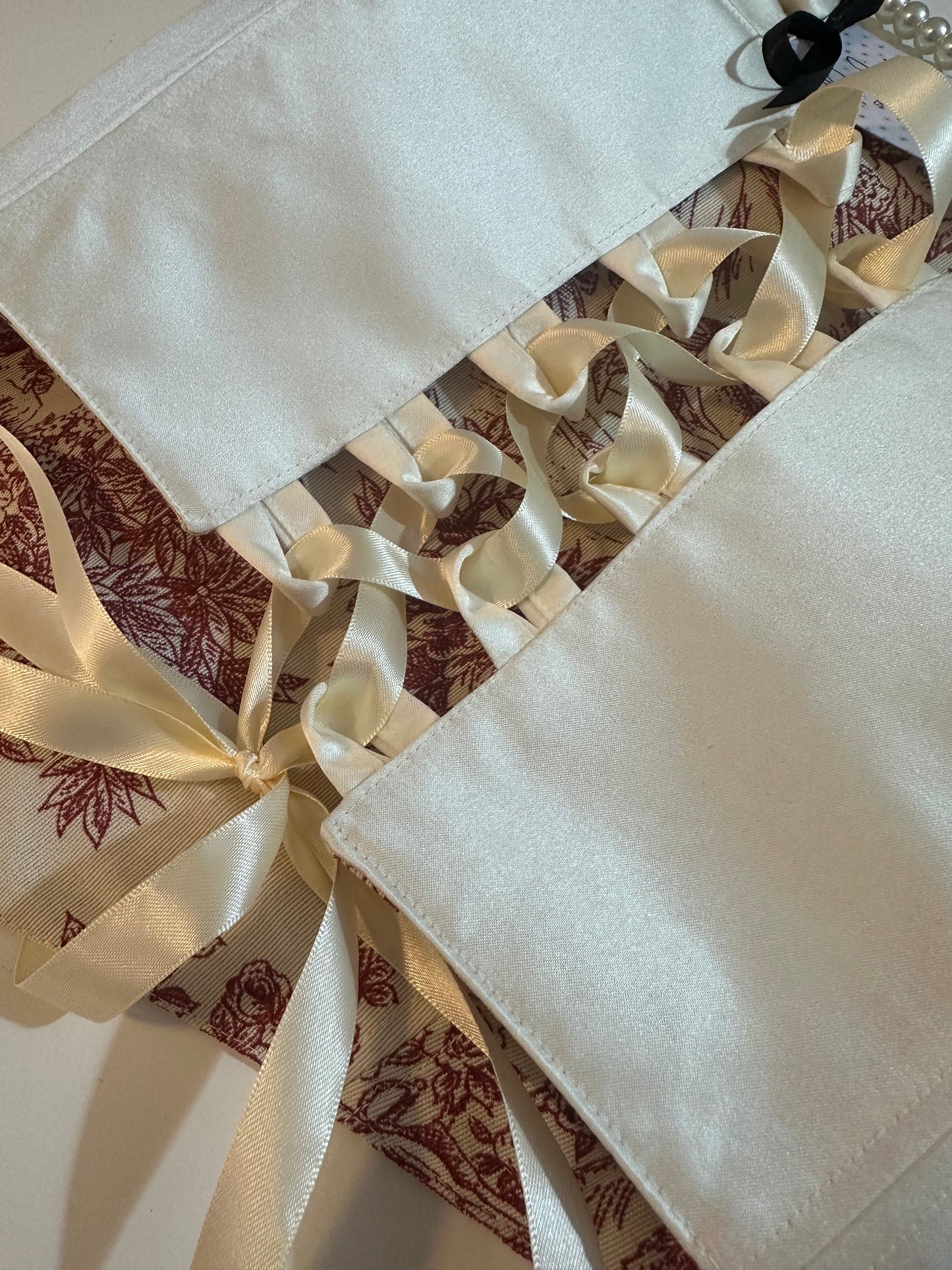 Decorative fabric with a patterned border and white fabric draped over it.