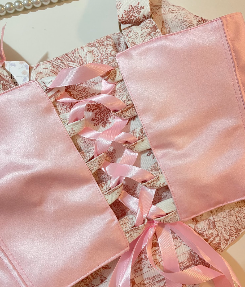 Pink satin fabric with ribbons on a floral-patterned surface