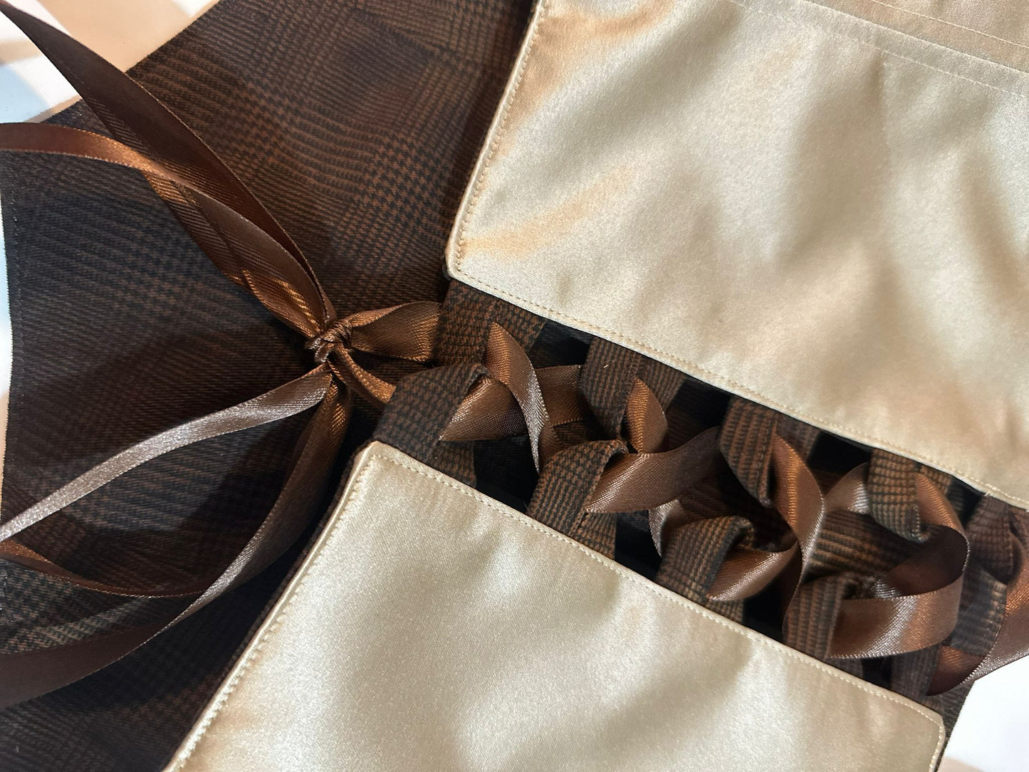 Close-up of a decorative corset top with brown ribbons on a beige fabric