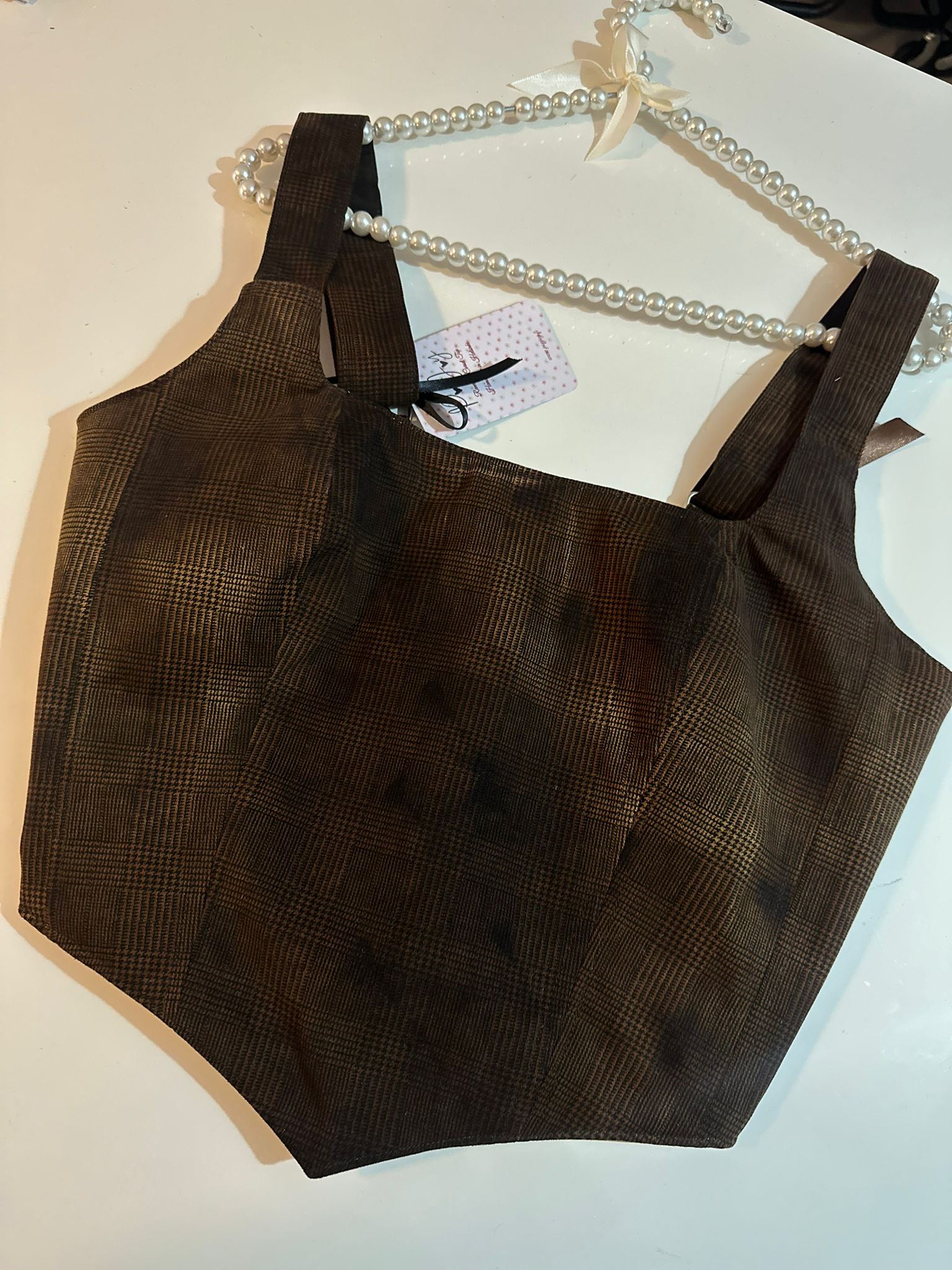 Brown sleeveless corset top on a hanger with a white background