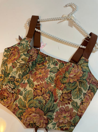 Floral-patterned corset top on a hanger with a pearls