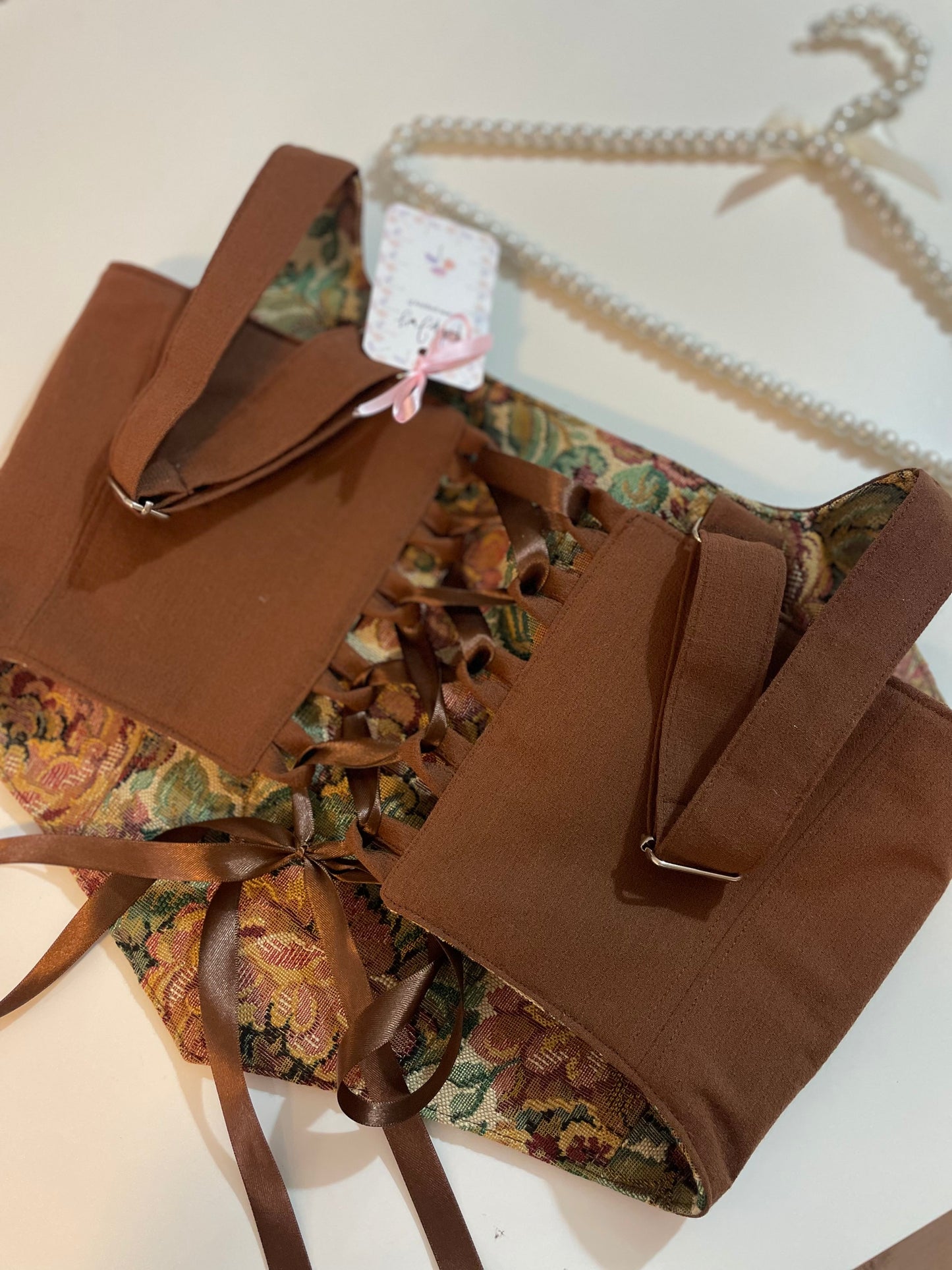 Brown corset top with floral interior on a white surface