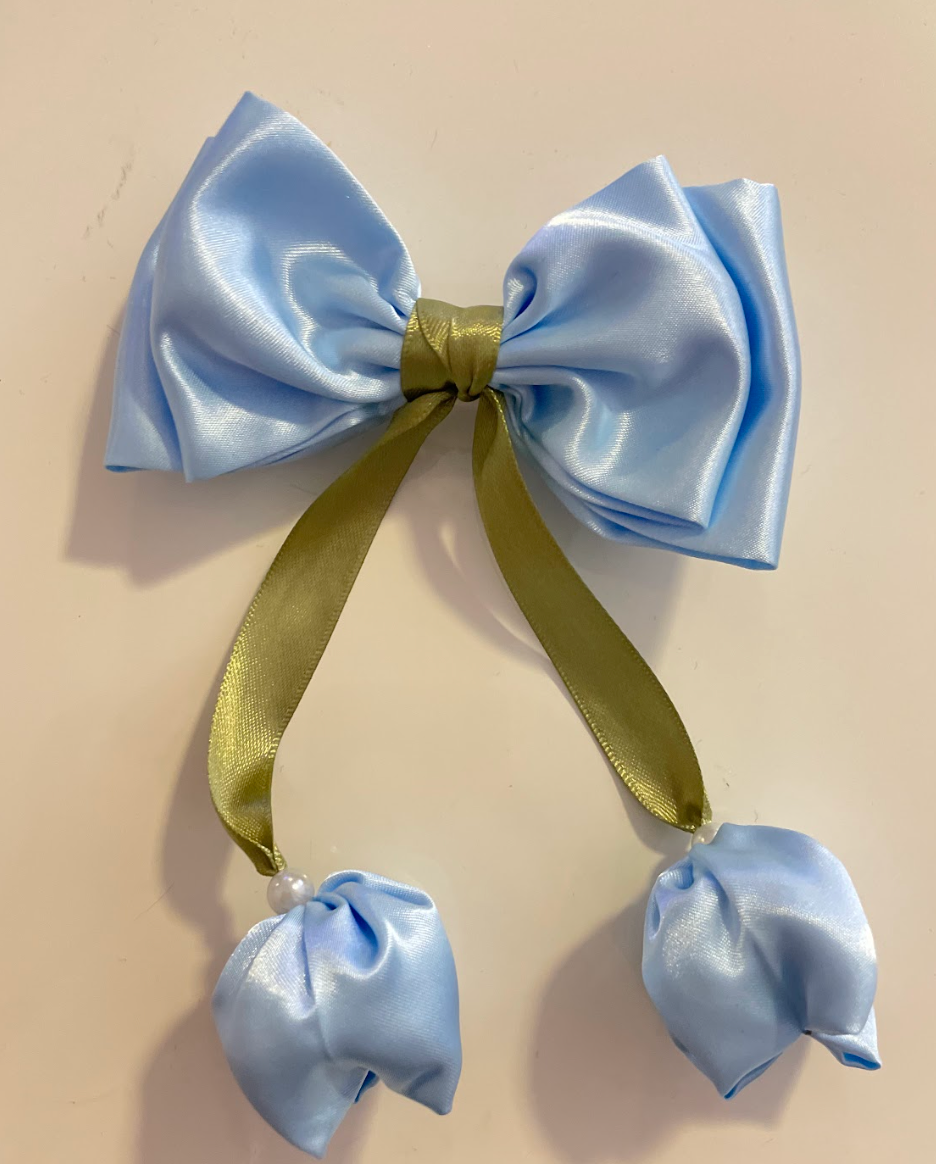 Light blue satin bow with green ribbon on a beige background
