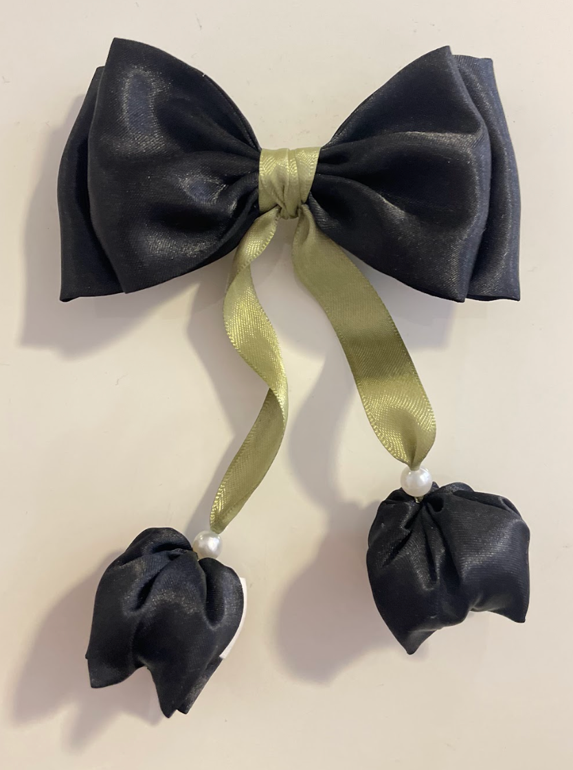 Black bow hair clip with green ribbon and black flowers on a beige background
