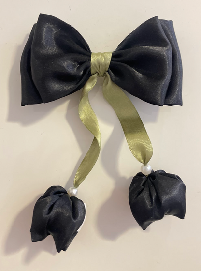 Black bow hair clip with green ribbon and black flowers on a beige background