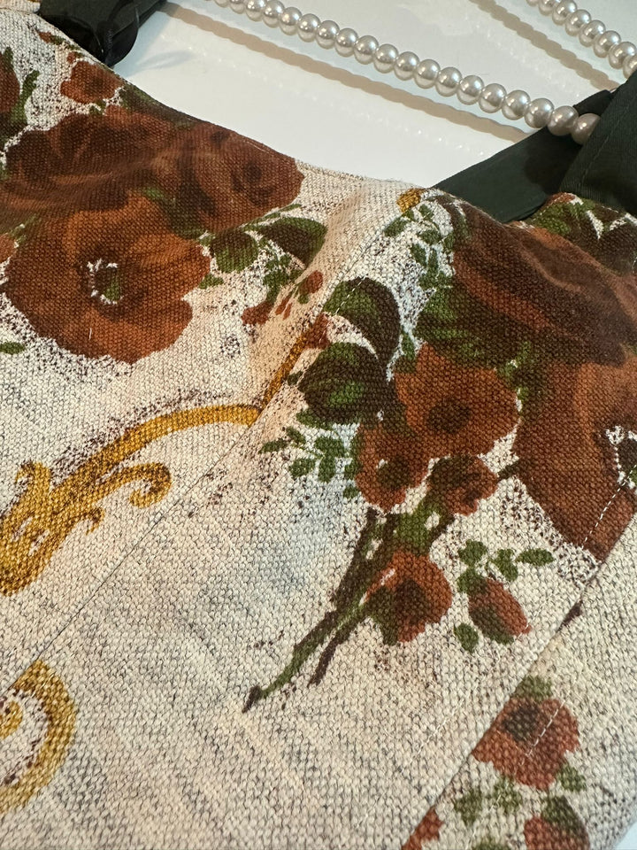 Close-up of a floral patterned fabric with brown flowers and green leaves.